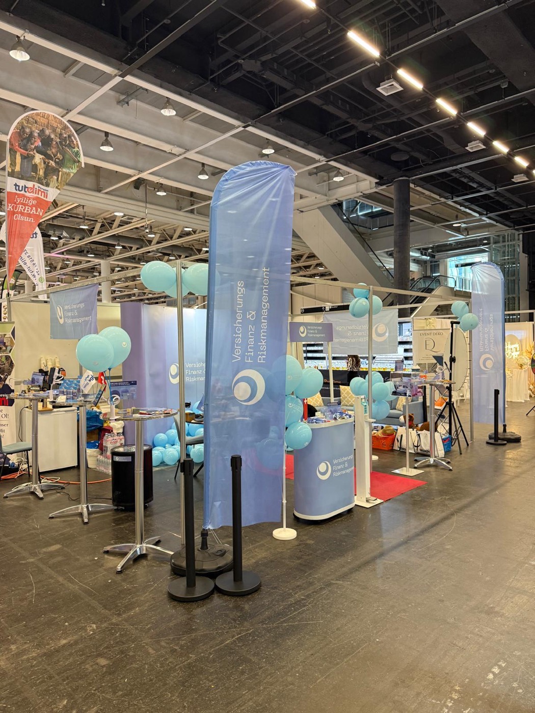 Messestand der VFR Versicherungs-, Finanz- und Riskmanagement GmbH mit Beachflags und Beratungstheke